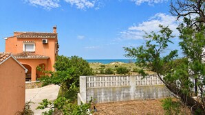 A coastal property with a Mediterranean-style building, a stone wall, and a view of the sea.