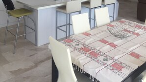 Una cocina moderna con gabinetes blancos, una isla central con taburetes altos y una lámpara colgante.