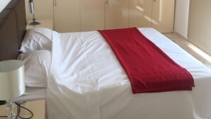 Un dormitorio con cama, mesita de noche, lámpara y armario.