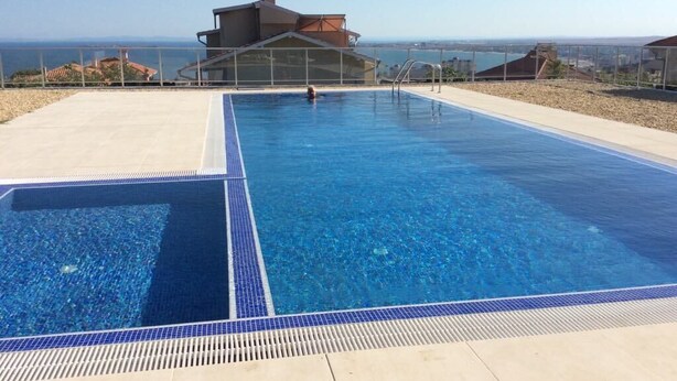Una piscina rectangular con agua cristalina y un borde de baldosas.