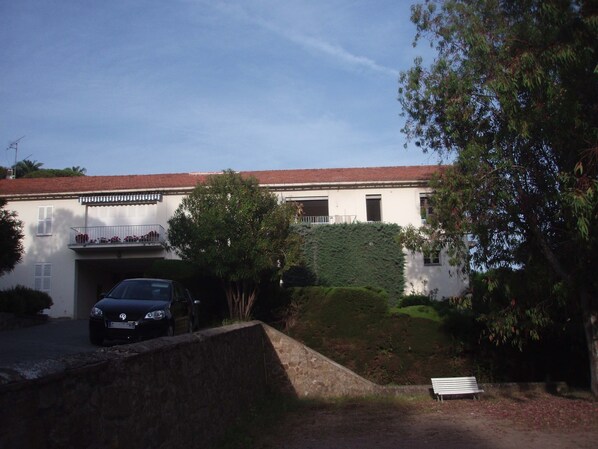A building with a red-tiled roof, a car parked in front, and a bench in the foreground. - Idyllic flat Cannes, sea view, 1. 200km Croisette, very calm (Cannes)