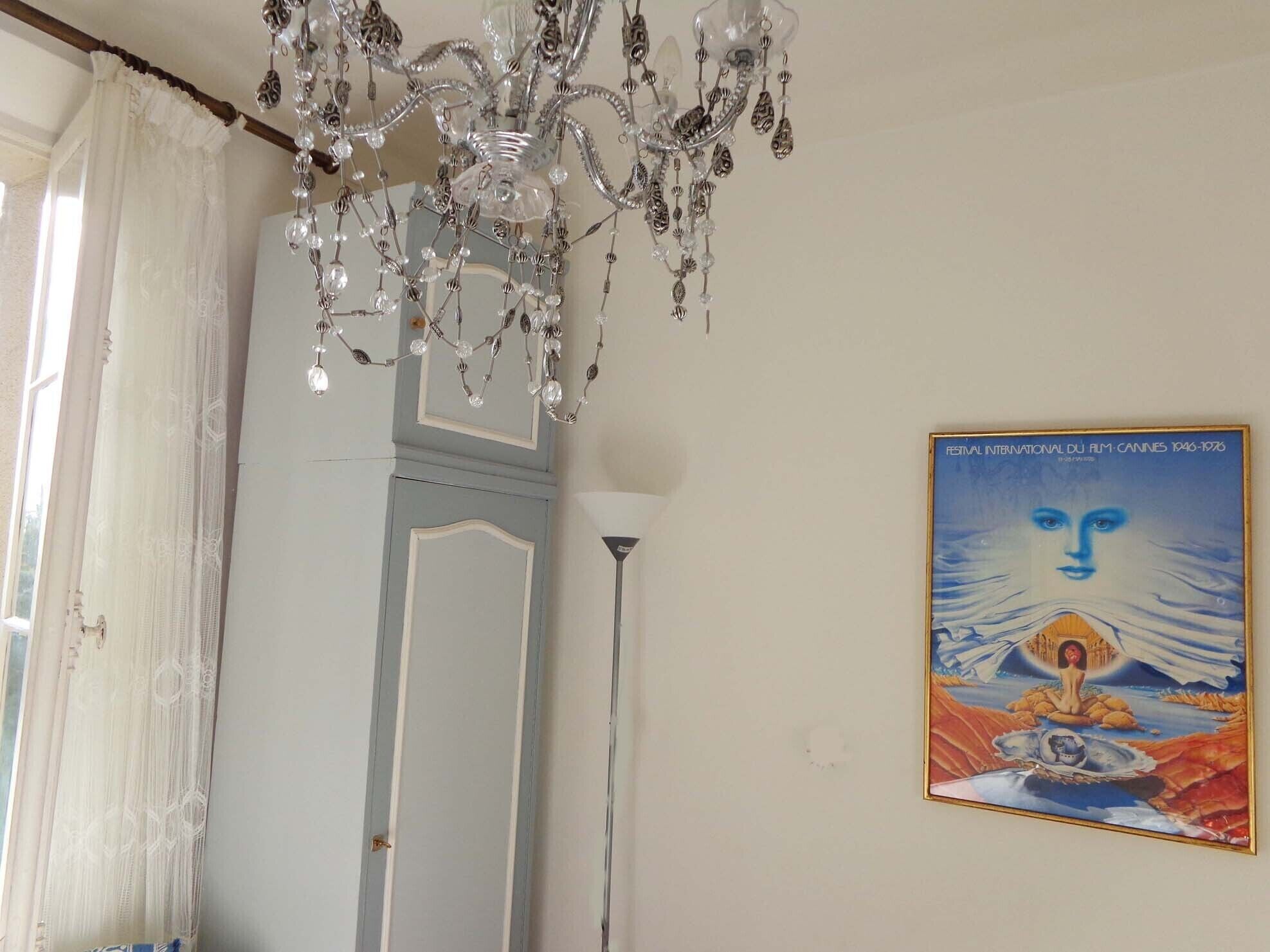 A room with a chandelier, a door, and a poster on the wall.