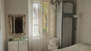 A bedroom with a bed, a dresser, a chair, a mirror with a decorative frame, a chandelier, and a wardrobe. - Idyllic flat Cannes, sea view, 1. 200km Croisette, very calm (Cannes)