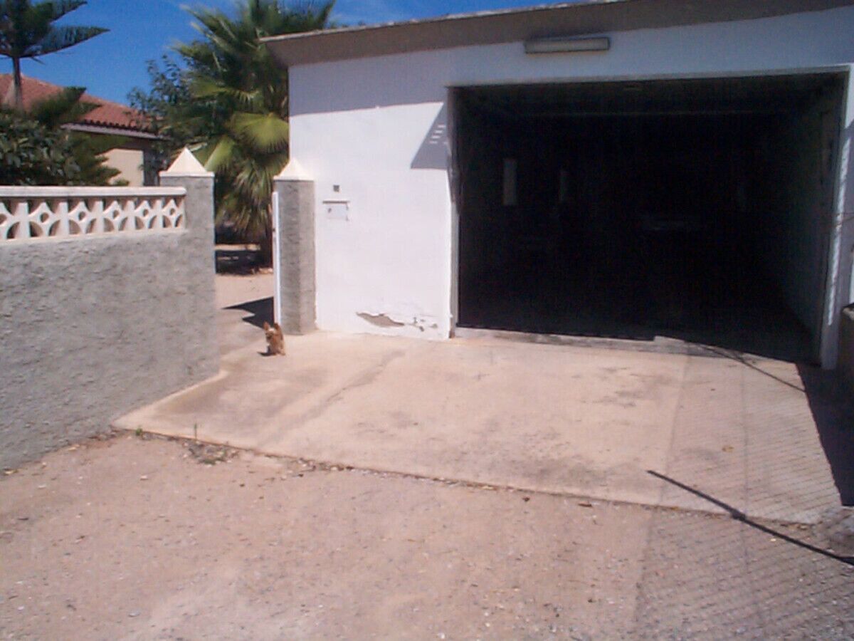 Entrada d'un edifici amb un camí de formigó que condueix a una porta de garatge.