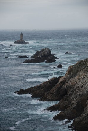 A rocky coastline with a lighthouse in the distance.