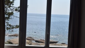 Una ventana con vista al mar y a la costa rocosa.