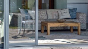 Una sala de estar moderna con un ventanal que da a un balcón, una mesa de centro de madera y un sofá estampado.