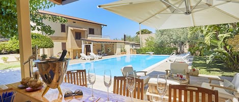 A poolside bar with a view of a swimming pool, lounge chairs, and a covered patio area.