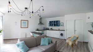 A modern living room with a sofa, a dining table, and a kitchen area with cabinets and appliances. - La maison de Valentine *** (Bordeaux)