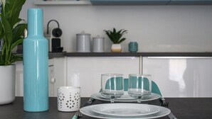 A neatly set dining table with plates, glasses, and cutlery, a teal water bottle, and a white mug with holes. - La maison de Valentine *** (Bordeaux)