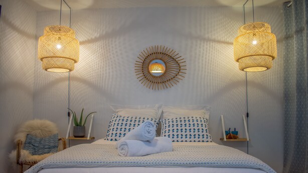 A neatly made bed with white linens, a round mirror on the wall, and two hanging lamps. - La maison de Valentine *** (Bordeaux)