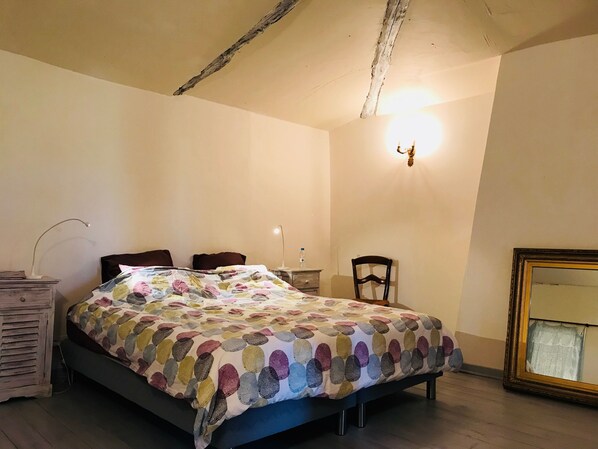 A bedroom with a bed, a chair, a dresser, a lamp, and a mirror.