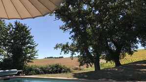 A swimming pool with a clear view of the surrounding landscape, including trees and a distant field.