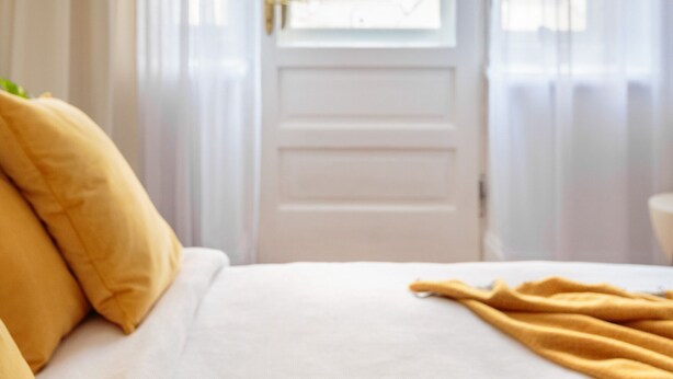 A room with a bed, a window with curtains, and a door. - Art Filled Apartment in the Heart of Riga (Riga)