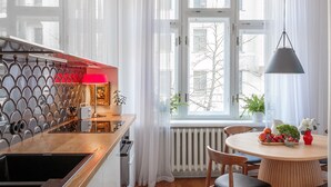 A modern kitchen with a wooden countertop, a red lamp, and a view of the city through large windows. - Art Filled Apartment in the Heart of Riga (Riga)