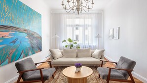 A modern living room with a beige sofa, two armchairs, a wooden coffee table, and a large abstract painting. - Art Filled Apartment in the Heart of Riga (Riga)