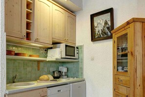 Kitchen area with a sink, microwave, and kettle, featuring a framed picture on the wall.