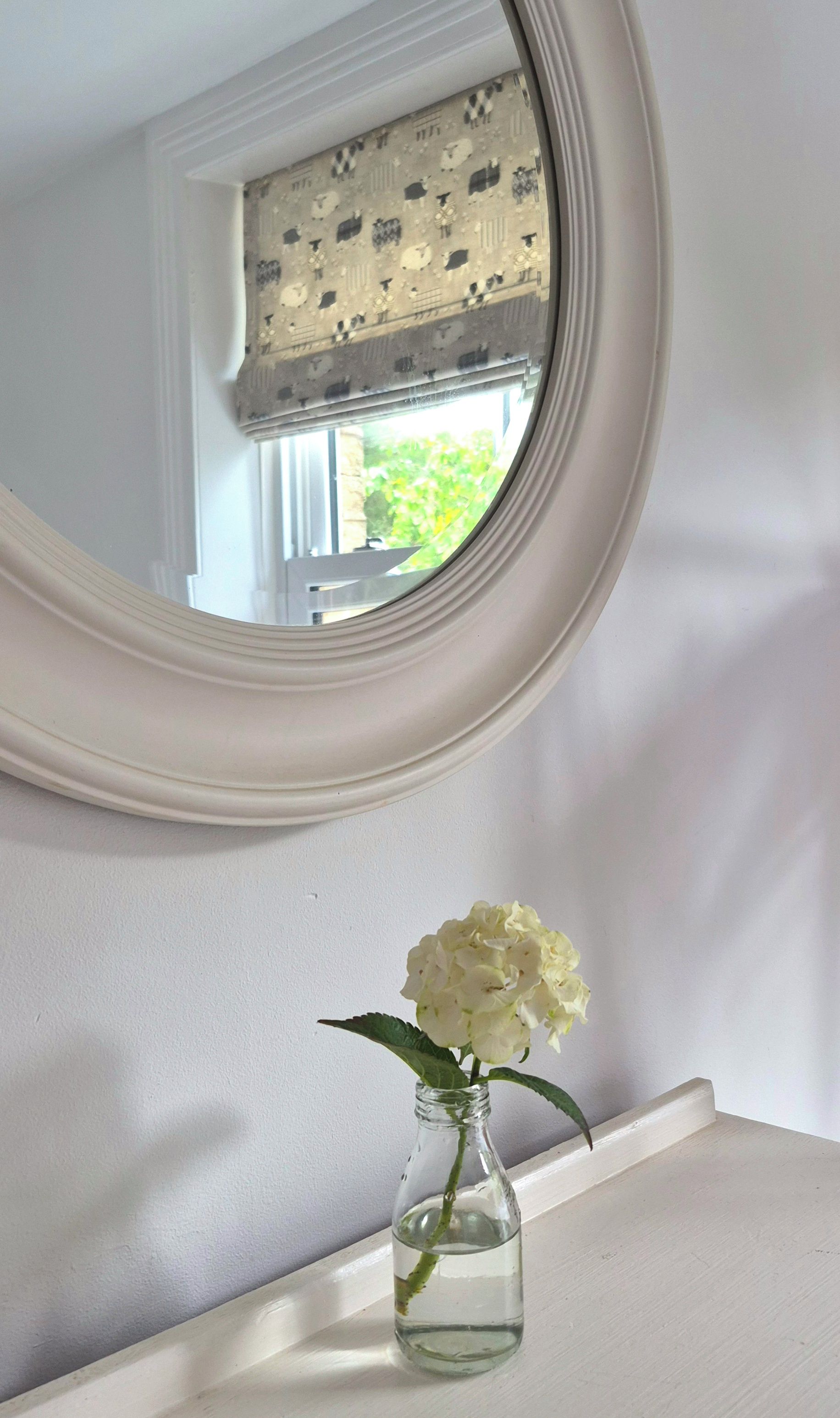 A white bathroom vanity with a round mirror above it.