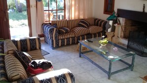 Ein Wohnzimmer mit einem gestreiften Sofa, einem Glastisch und einem Kamin.