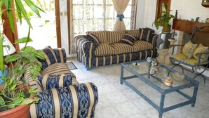 Ein Wohnzimmer mit gestreiften Sofas, einem Glastisch und Topfpflanzen.