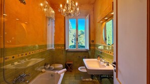 A bathroom with a bathtub, a sink, and a window providing a view of trees. - RELAIS VILLA LINA LANDMARK ORGANIC FARM TUSCIA ROME 18th century (Ronciglione)