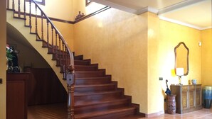 A wooden staircase with a handrail, leading to a landing with a vase and a lamp. - Villa Mercè. Golden Coast (Botarell)