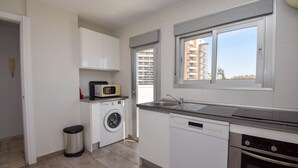A modern kitchen with a washing machine, dishwasher, and oven.