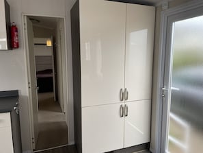 Une chambre d’hôtel avec un placard, une porte en verre dépoli et un couloir menant à un lit.