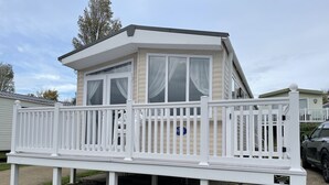 A mobile home with a white deck and a covered porch. - Rambling Rose caravan with sea view on Rockley Park (Poole)