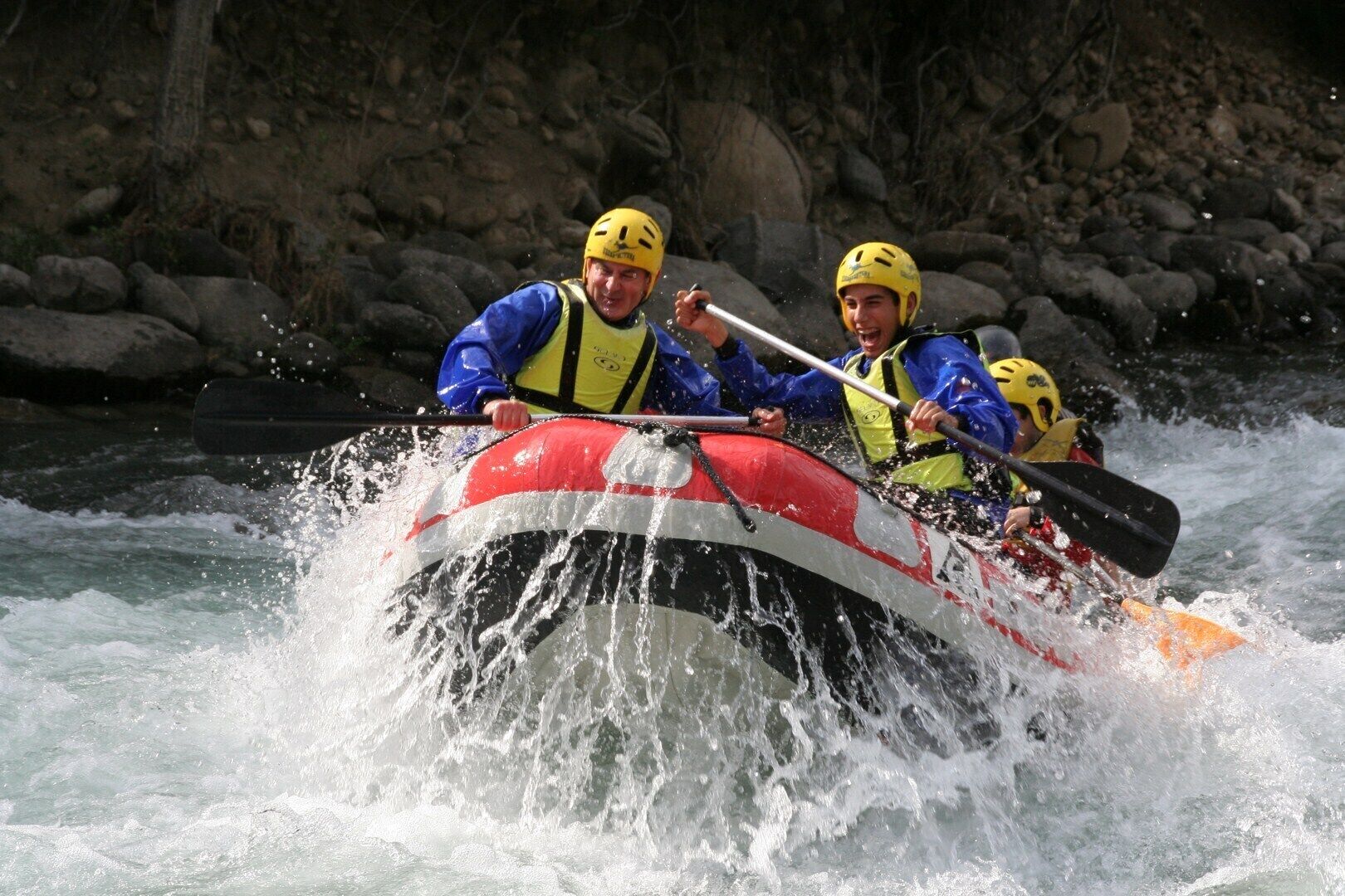 A group of people in a raft navigating through a river with rapids.