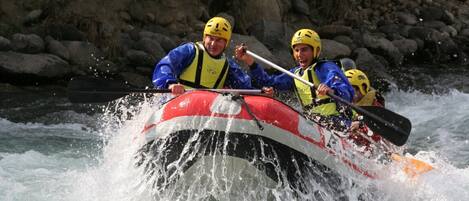A group of people in a raft navigating through a river with rapids.