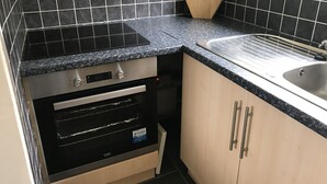 Una cocina con salpicadero de azulejos negros, encimera de granito, horno empotrado y pileta de acero inoxidable.