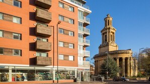 A multi-story building with a brick facade, a central tower with columns, and a storefront with a sign that reads "TESCO EXPRESS". - Skyline Birmingham City Centre Penthouse (Birmingham)