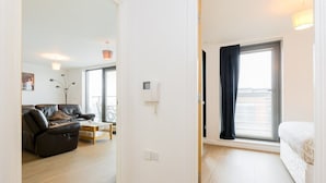 A modern apartment with a living room, a bedroom with a large window, and a small dining area. - Skyline Birmingham City Centre Penthouse (Birmingham)