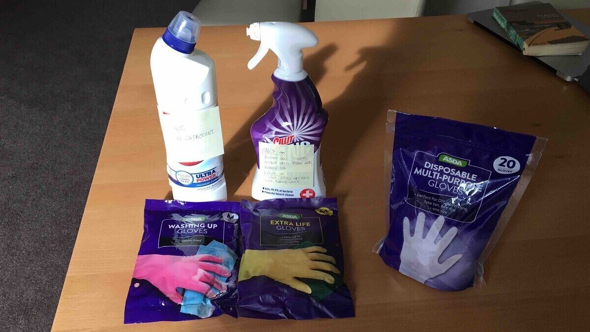 Une table contenant du matériel de nettoyage, notamment une bouteille de produit Ultra Power, un flacon pulvérisateur et deux paquets de gants.