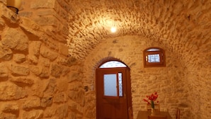 A stone-walled room with a wooden door and a small window.