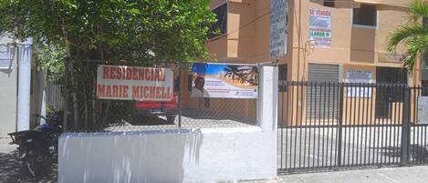 A residential property with a gated entrance, a sign advertising a residential property, and a parked motorcycle.
