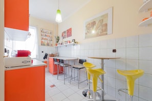 Una cocina moderna con azulejos blancos, un electrodoméstico rojo y taburetes amarillos.