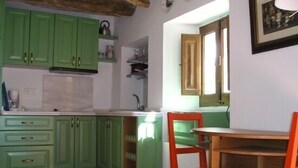 A kitchen with green cabinets, a wooden table, and a red chair. - Casa Ábalos, in the middle of nature (Periana)