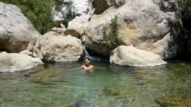 A person swimming in a clear, rocky stream surrounded by large boulders. - Casa Ábalos, in the middle of nature (Periana)