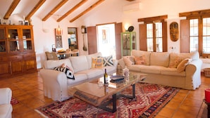 A spacious living room with high ceilings and exposed beams, featuring two sofas, a coffee table, and a patterned rug. - Five stars reviews - Peaceful - Fantastic pool - Privacy & Long views (Jávea)