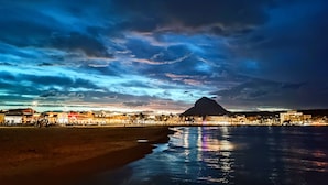A coastal town with a prominent mountain in the background, a beach, and a body of water reflecting lights. - Five stars reviews - Peaceful - Fantastic pool - Privacy & Long views (Jávea)
