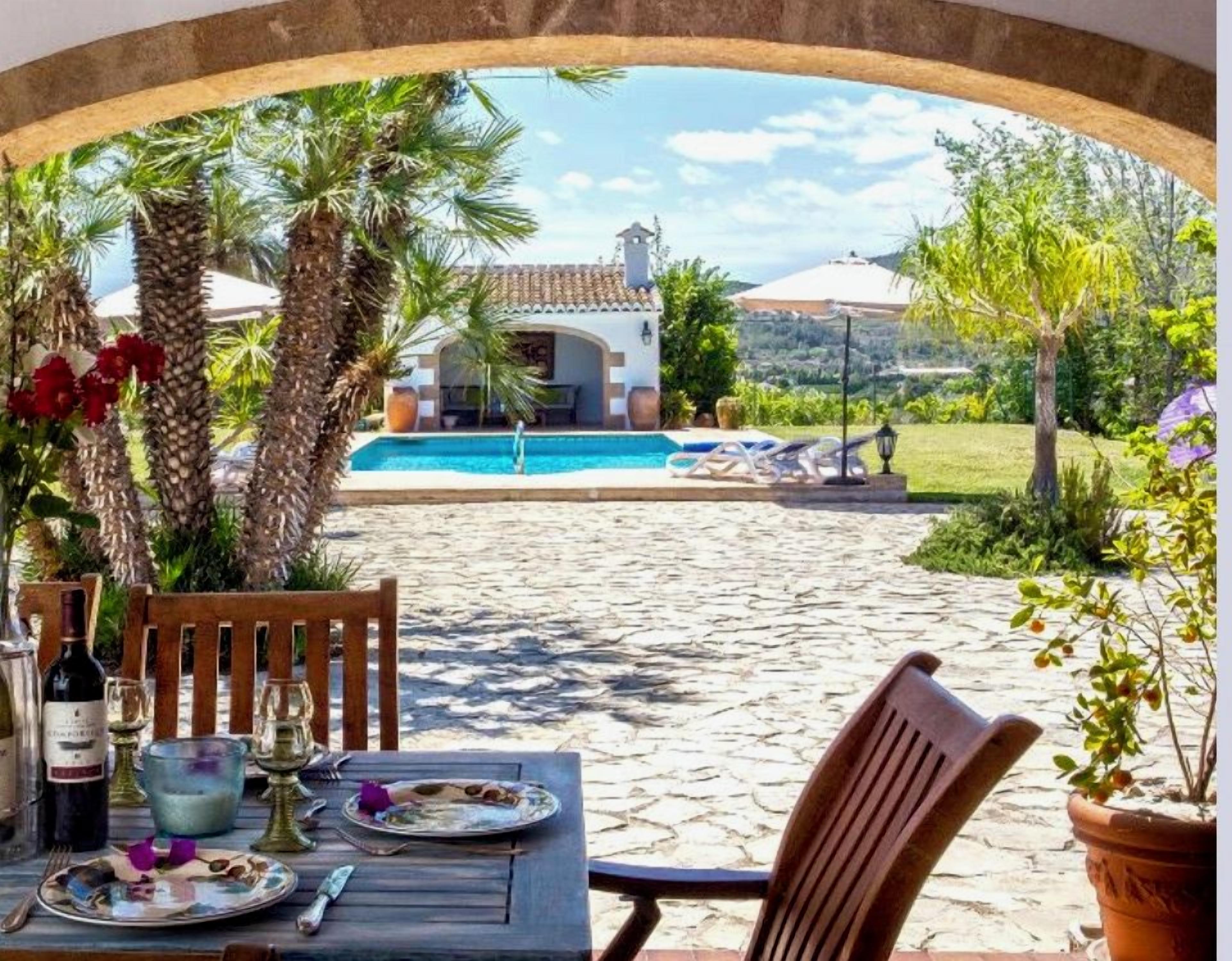 A table set for dining with a view of a pool and villa in the background.