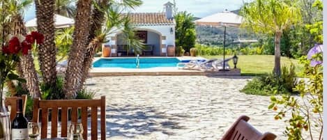 A table set for dining with a view of a pool and villa in the background.