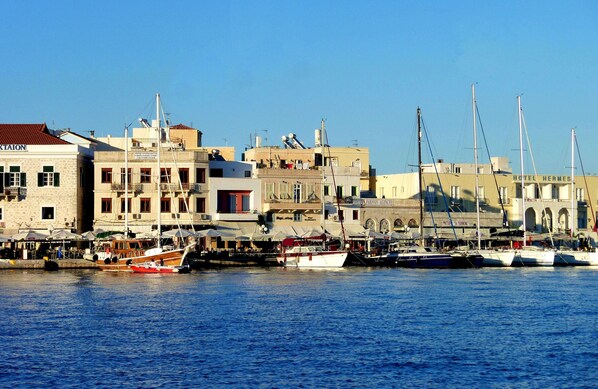A marina with boats docked, buildings with signage, and a clear sky.