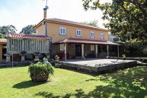 A two-story house with a covered patio and a small garden area.