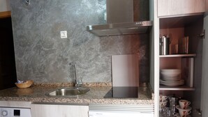 A compact kitchen with a stainless steel sink, a built-in washing machine, and a microwave.