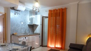 A compact living space with a dining area, kitchenette, and a sofa.