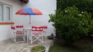 Een terras met een tafel en stoelen, een bloempot en een kleine tuin.