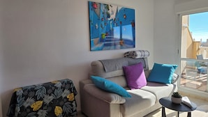 Ein Wohnzimmer mit einer Couch, einem kleinen Tisch und einem Gemälde an der Wand.